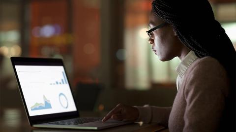 Woman creating presentation on laptop in dark office